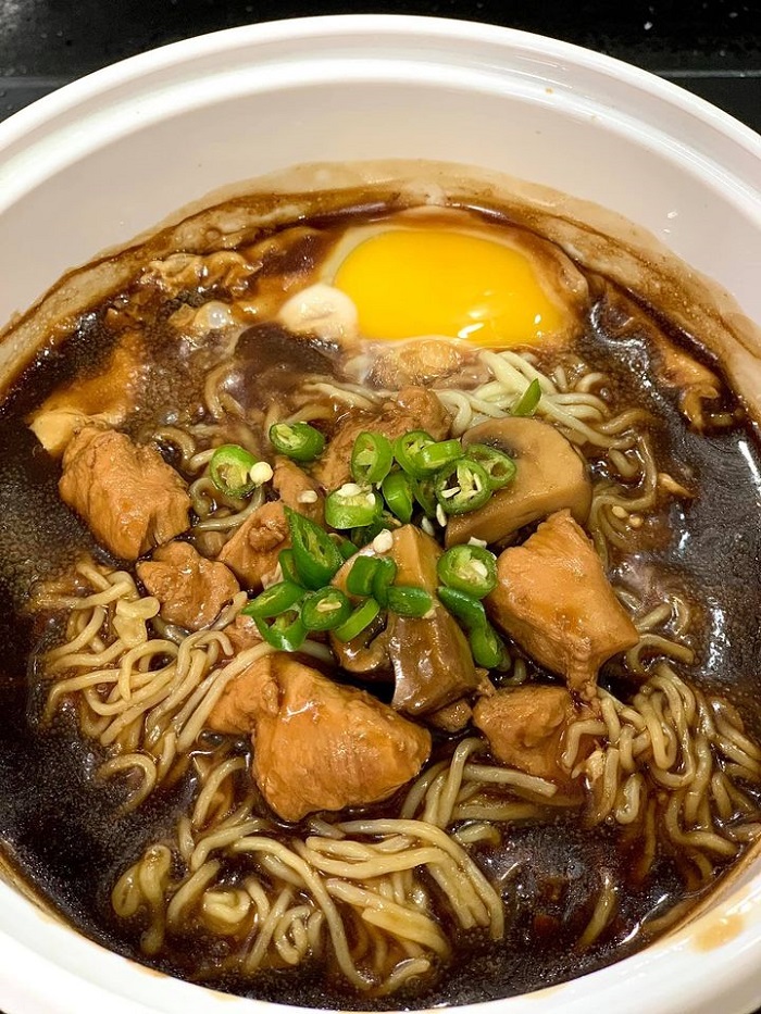 Sizzling mee claypot berasap dihidang panas dengan kuah sos kicap, telur dan cili potong.
