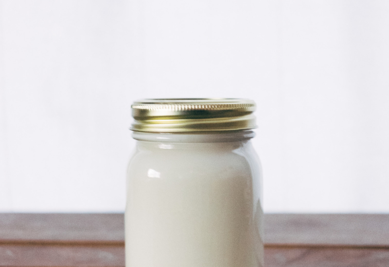 Semangkuk yogurt putih yang segar dengan beberapa biji buah beri di atasnya.