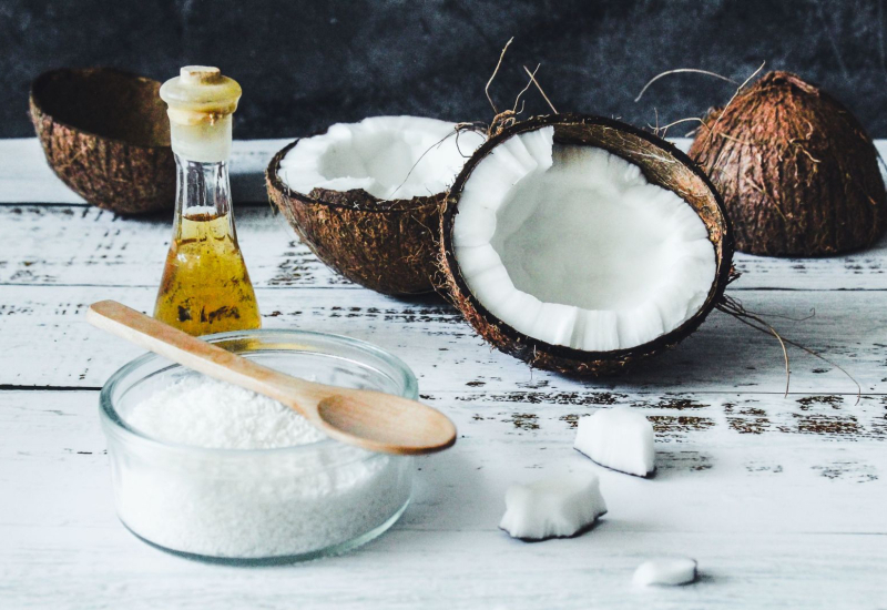 Botol minyak kelapa dara bersama kelapa pecah sebagai latar belakang