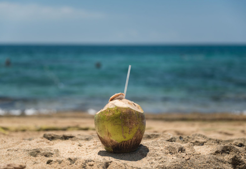 Imej buah kelapa muda yang dibelah beserta segelas air kelapa jernih