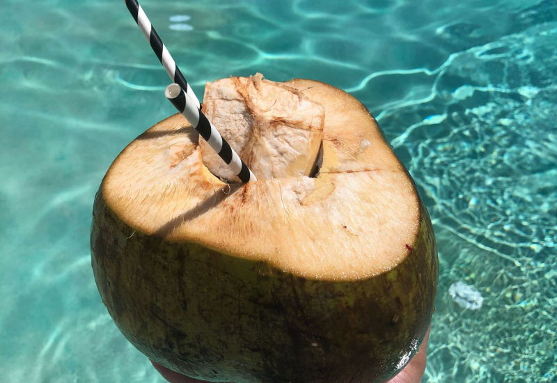 Segelas air kelapa jernih dengan potongan isi kelapa