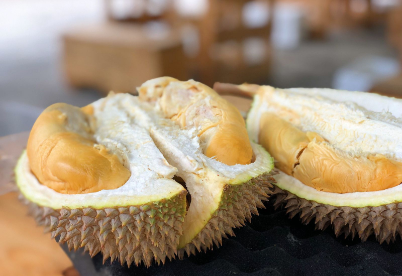 Buah durian dibuka memaparkan isi yang kuning dan ranum