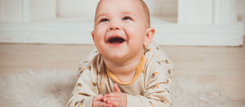 Gambar bayi sedang tumbuh gigi dengan ibu jari dimasukkan ke dalam mulut.