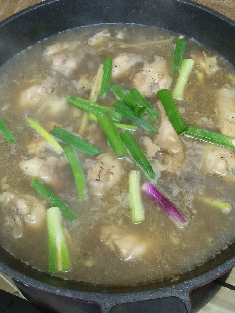 Sebuah mangkuk berisi sup ayam panas dengan hirisan halia dan lada hitam yang sedap
