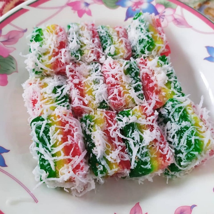 Sepotong kuih talam sagu ubi tiga lapis berwarna hijau, kuning dan merah yang telah siap dipotong.