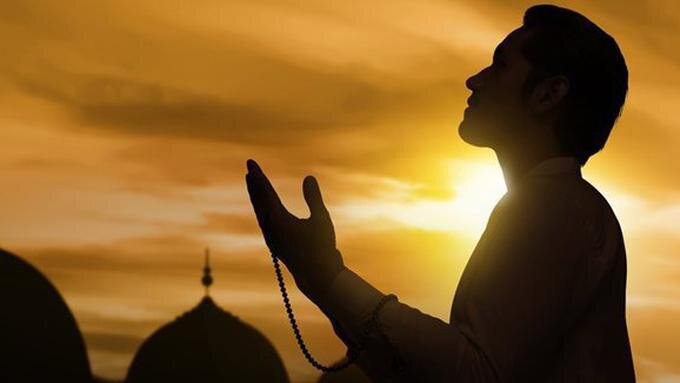 Ilustrasi lelaki muslim berdoa menunduk dengan latar belakang masjid bagi menceritakan taubat nasuha.