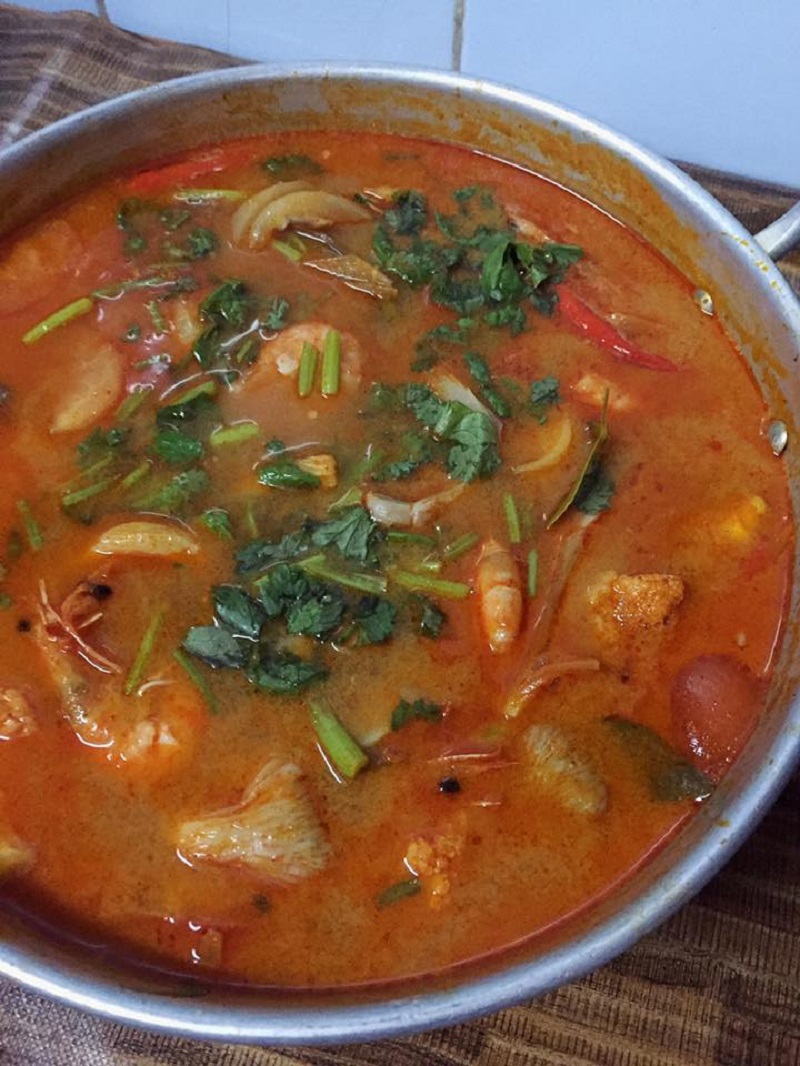 Sebuah mangkuk berisi sup Tom Yam Thai yang berasap dengan seafood dan sayur-sayuran.