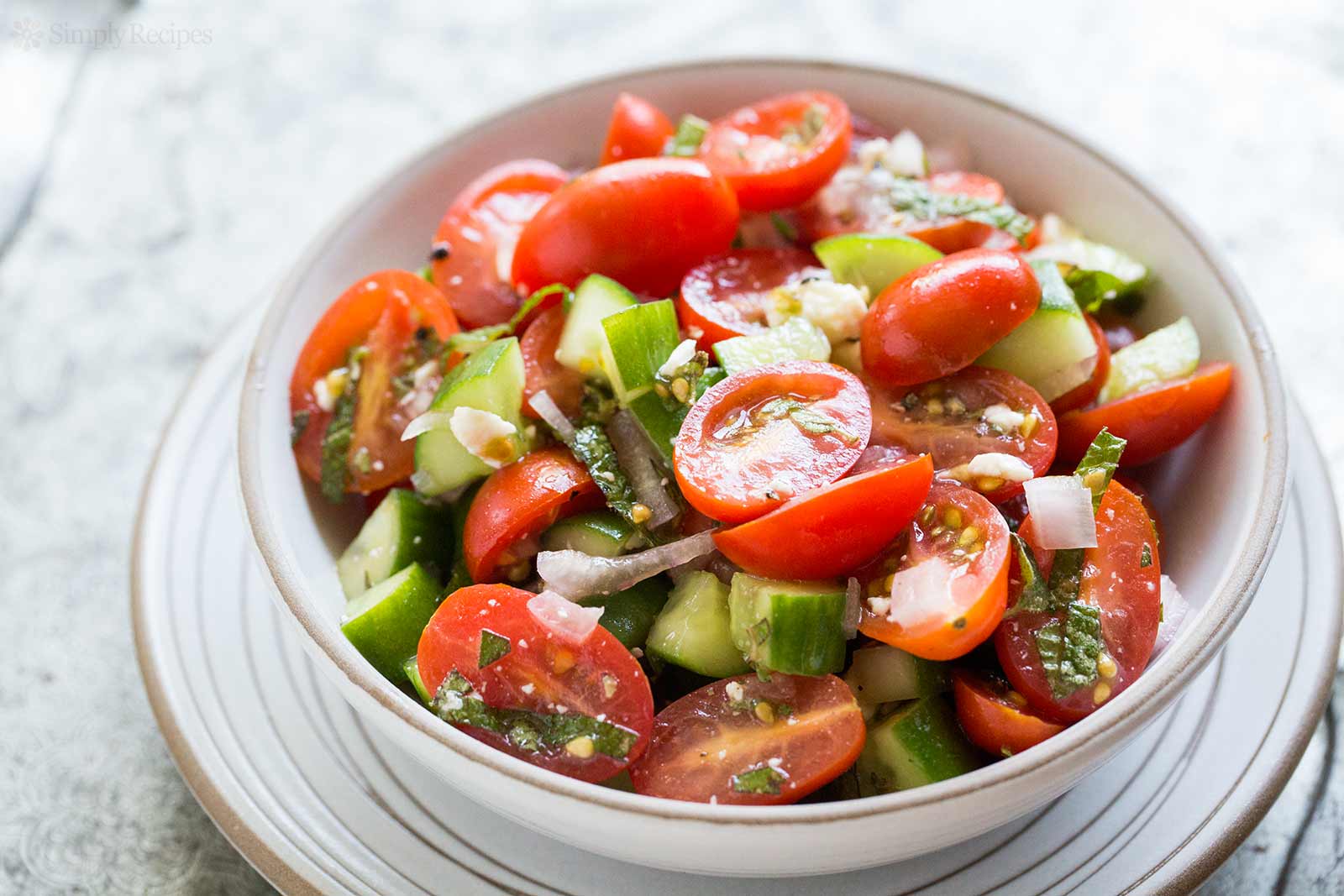 Pinggan salad tomato ceri, timun dan keju fata yang segar sebagai contoh makanan rendah kalori.