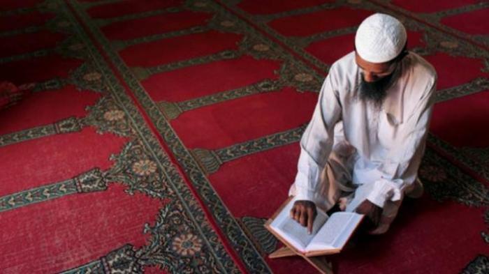 Umat muslim lelaki sedang membaca kitab suci al-Quran.