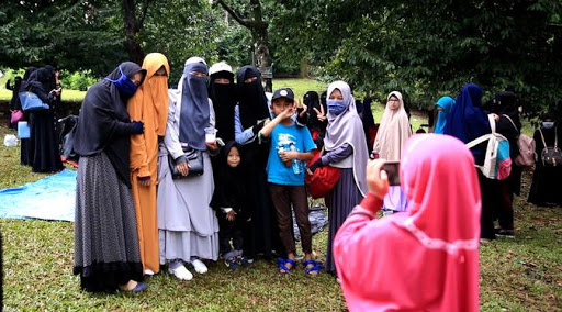Sekumpulan wanita berpurdah hitam duduk bersama