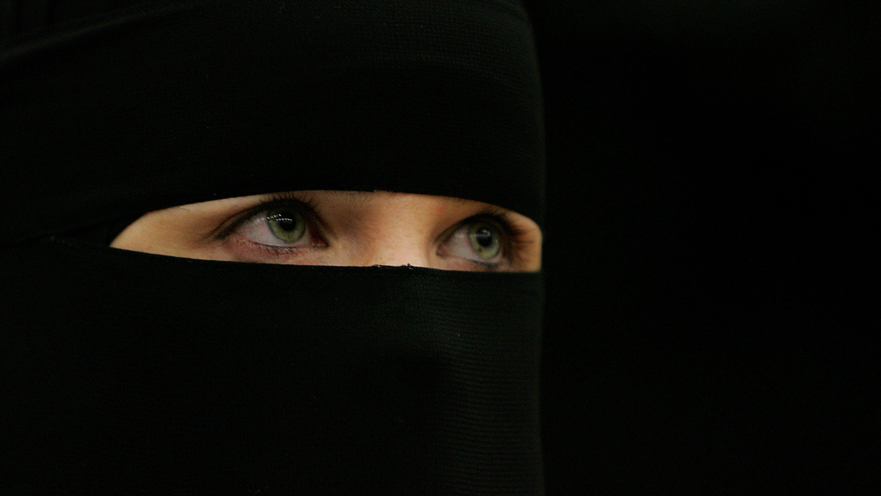 Wanita berpakaian hitam dan bertudung menunduk dengan wajah sedih.