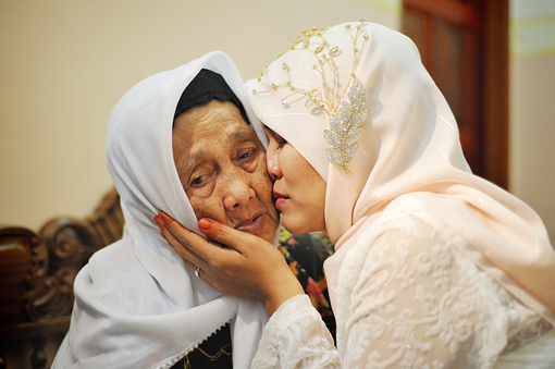 Gambar seorang anak sedang berbuat baik dan berbakti kepada ibu bapa yang berusia.